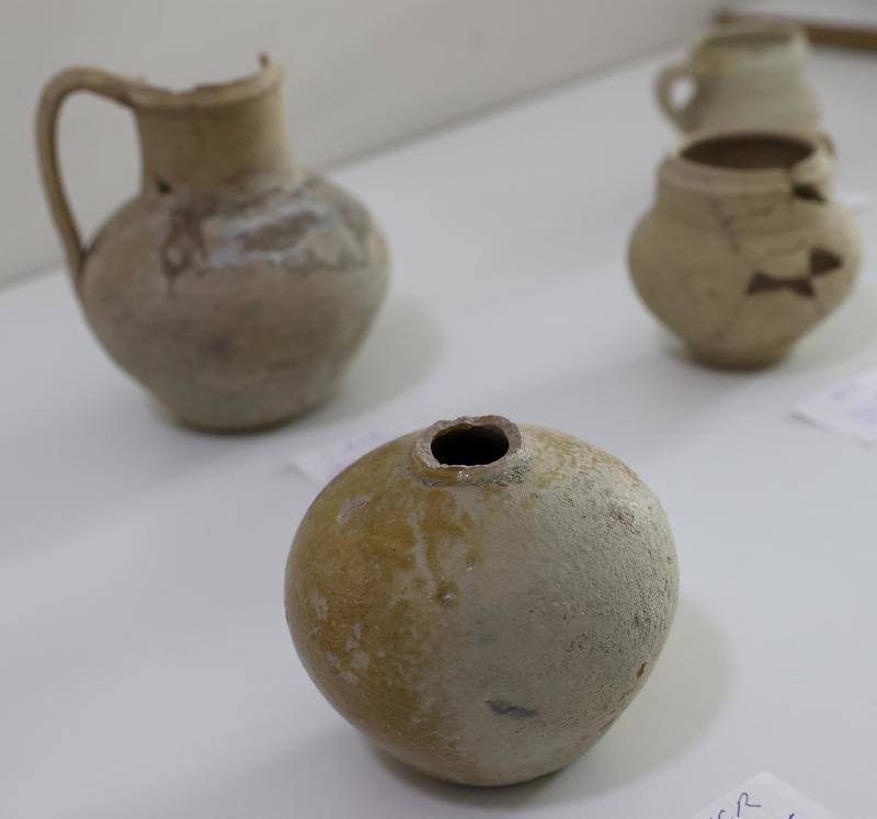 En primer plano, una botellita del siglo X a la que le falta el cuello