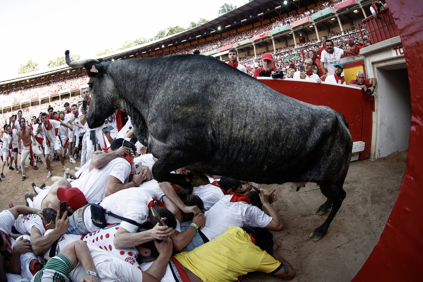 Una vaquilla salta por encima de un grupo de corredores a su salida del toril en la plaza de toros tras el tercer encierro de los sanfermines 2023, este domingo en Pamplona