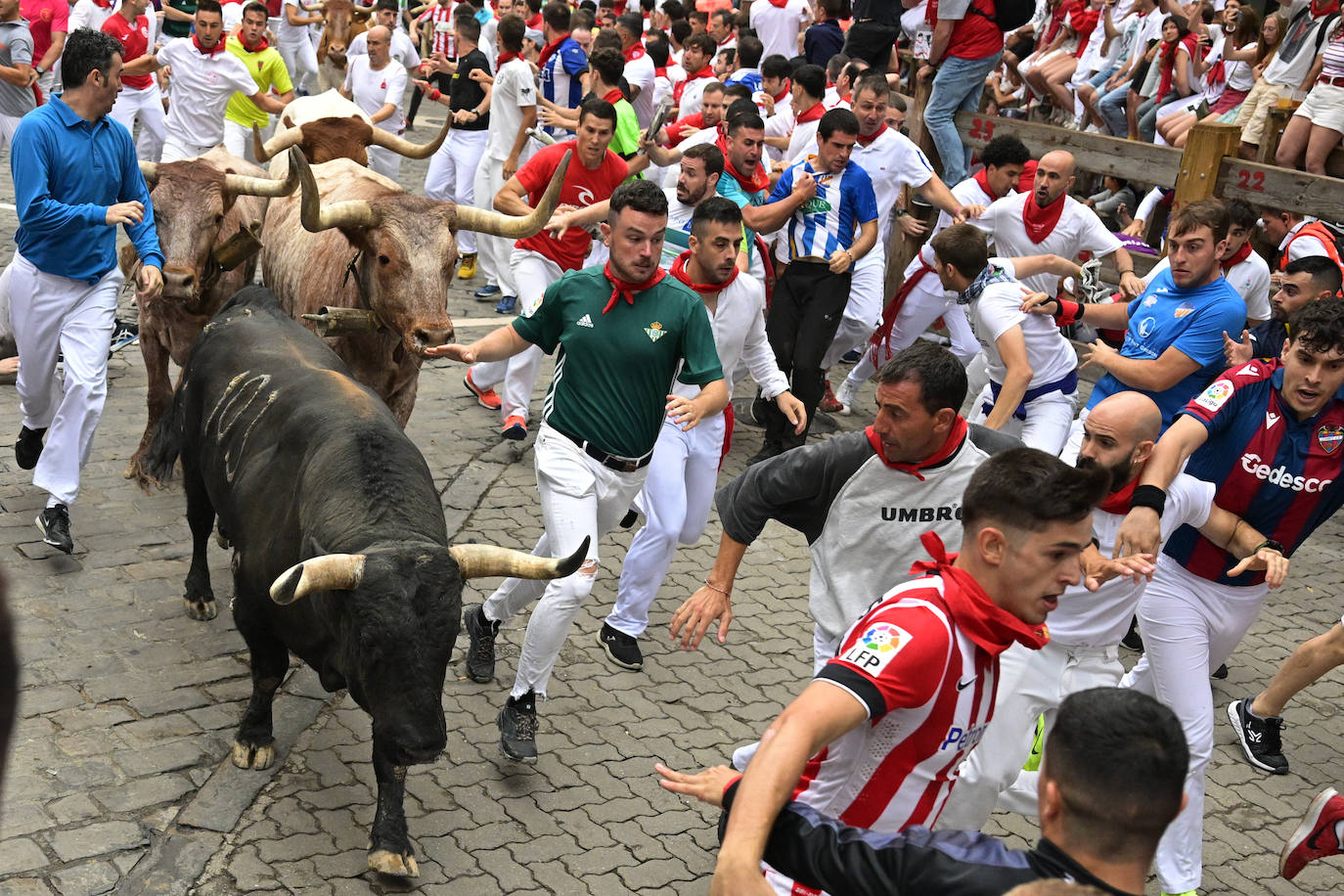 Corredores junto a los toros durante el quinto encierro de las fiestas de San Fermín 2023