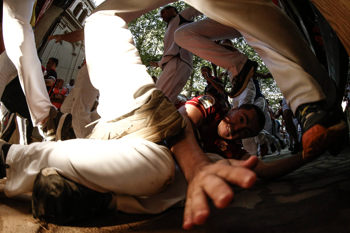 Un mozo caído, durante del séptimo encierro de los sanfermines con toros de la ganadería de Victoriano del Río