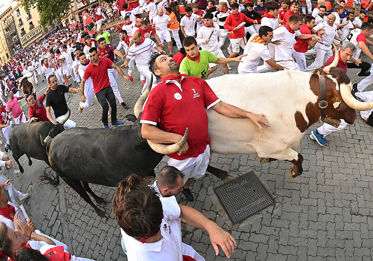 Un mozo corre entre un Miura y un manso