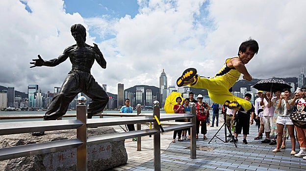 El actor chino Mei Zhiyong, realiza una patada voladora frente a la estatua de Bruce Lee en Tsim Sha Tsui