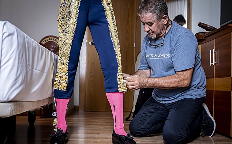 Imagen principal - Paco Robleño, tío del matador y modo de espadas, le ayuda a vestir el humano miedo de valor de luces. Aún está reciente la cicatriz de los Sanfermines. Robleño pide silencio y extiende sus estampas sobre la cama. 