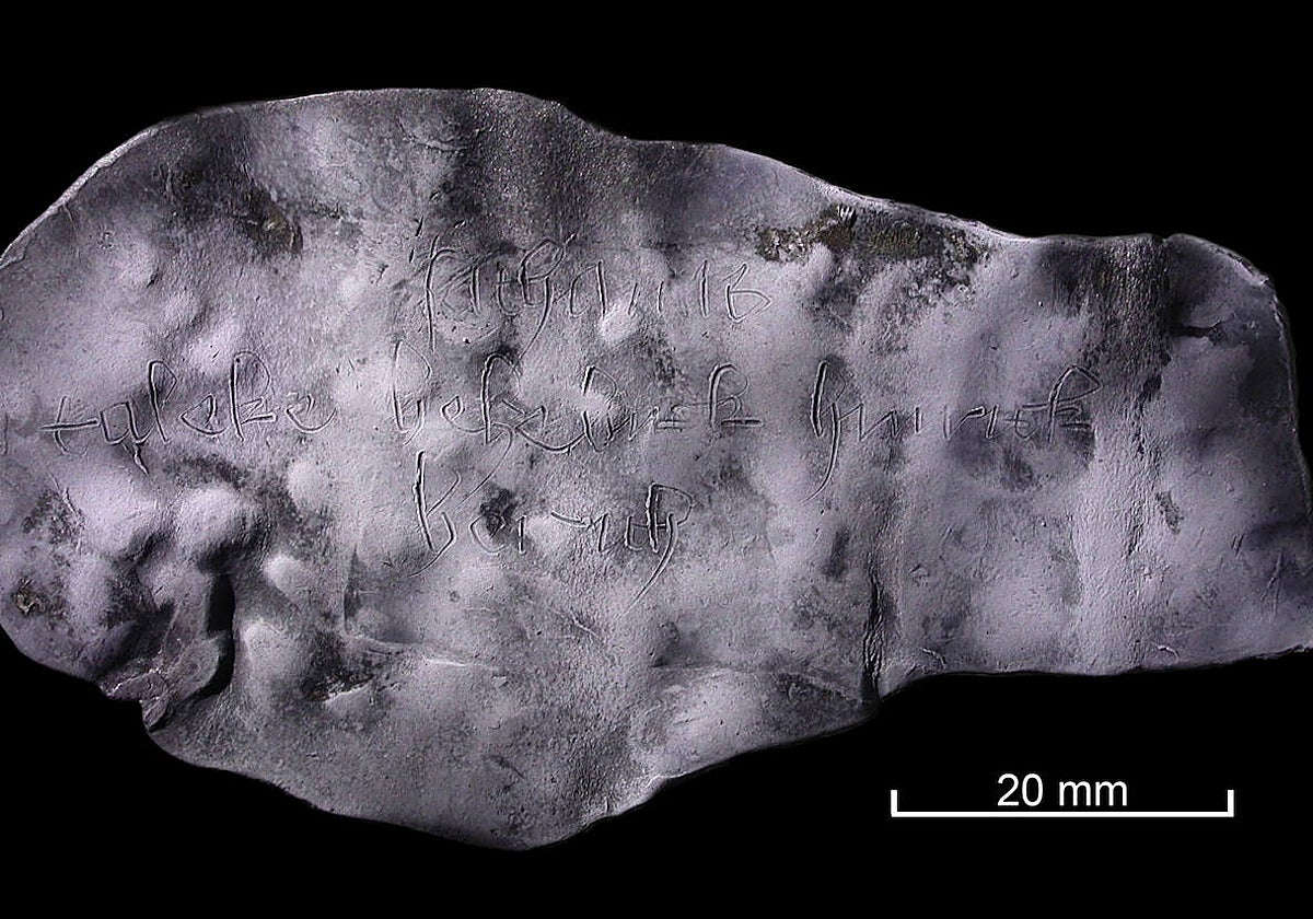 El trozo de plomo enrollado contiene inscripciones apenas visibles a simple vista