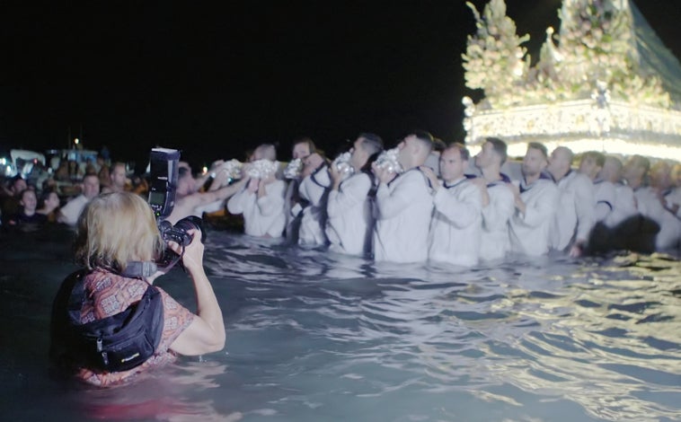 Imagen principal - Arriba, fotograma de 'La mirada oculta', documental dirigido por Carlota Nelson, en el que Cristina García Rodero aparece con el agua al cuello en la procesión de la Virgen del Carmen en Los Boliches (Málaga). Sobre estas líneas, a la izquierda, otro fotograma del documental con García Rodero chamuscada en El Vítor (Mayorga, Valladolid); a la derecha, portada original de 'España oculta', que se reedita 35 años después