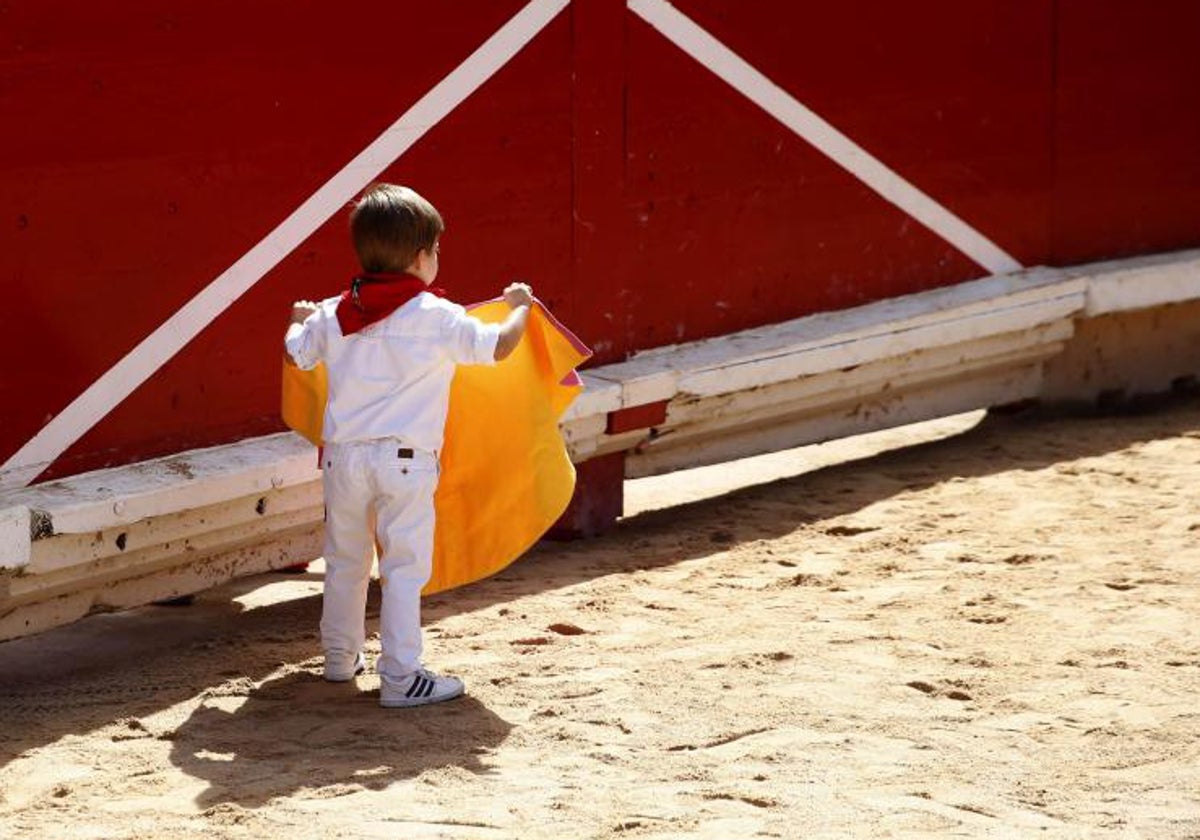 Un niño con su capotillo en un acto en familia en una plaza de toros