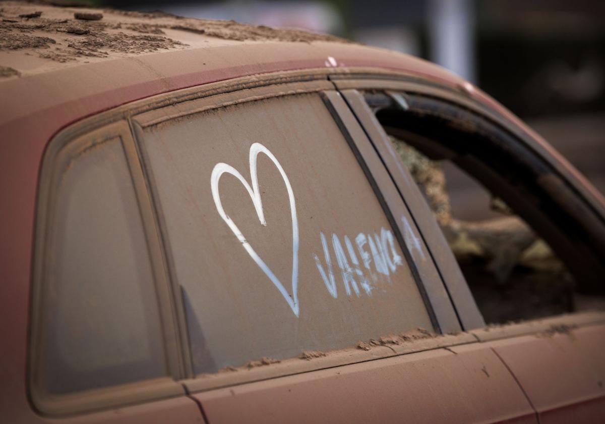 Un corazón pintado en un coche cubierto de polvo en Paiporta