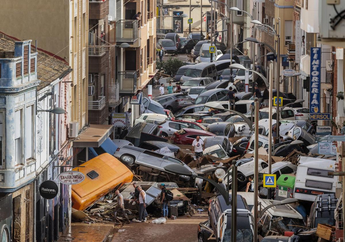 Decenas de vehículos apilados en una calle de Sedaví tras ser arrastrados por la corriente durante la dana