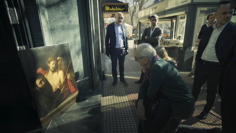 Fotograma de 'The Sleeper. El Caravaggio perdido', en el que los especialistas del pintor contemplan el cuadro en la calle, a plena luz del día