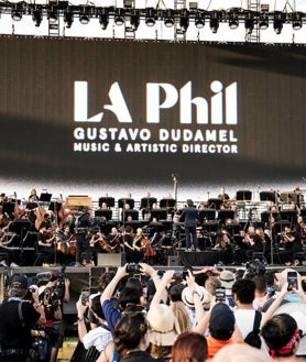 Imagen secundaria 2 - Arriba, un joven Dudamel dirigiendo una orquesta de El Sistema (Foto: El Sistema). Derecha, Dudamel junto a El Sistema en la Philarmonie de Paris (Foto: Bertrand). Izquierda, Dudamel junto a la LA Phil en Coachella (Foto: Timothy Norris)