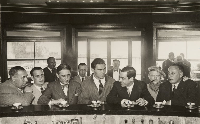 Imagen principal - Daniel Strauss, arriba con el boxeador Max Schmeling (3) y Josep Maria Massip i Izàbal (2), director de La Humanitat, organo de la Esquerra Republicana de Catalunya, tomando un café en un establecimiento de Sitges. Abajo con el presidente de la Generalidad de Cataluña, Lluis Companys (en el centro, con traje claro) el boxeador Max Schmeling, a la derecha de éste, en una visita al antiguo Palacio de la Diputación provincial de Barcelona.