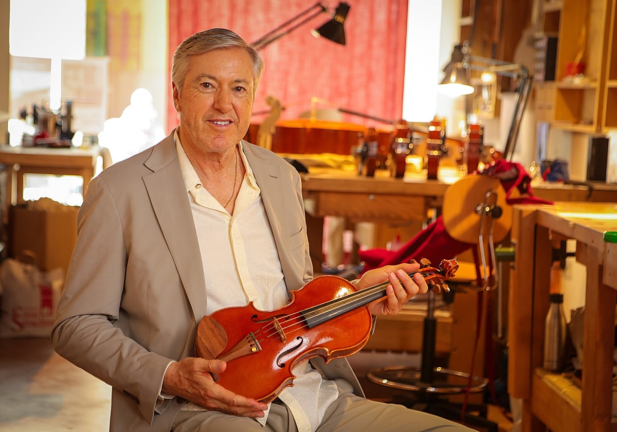 Alejandro G. Roemmers sosteniendo un violín en una lutería