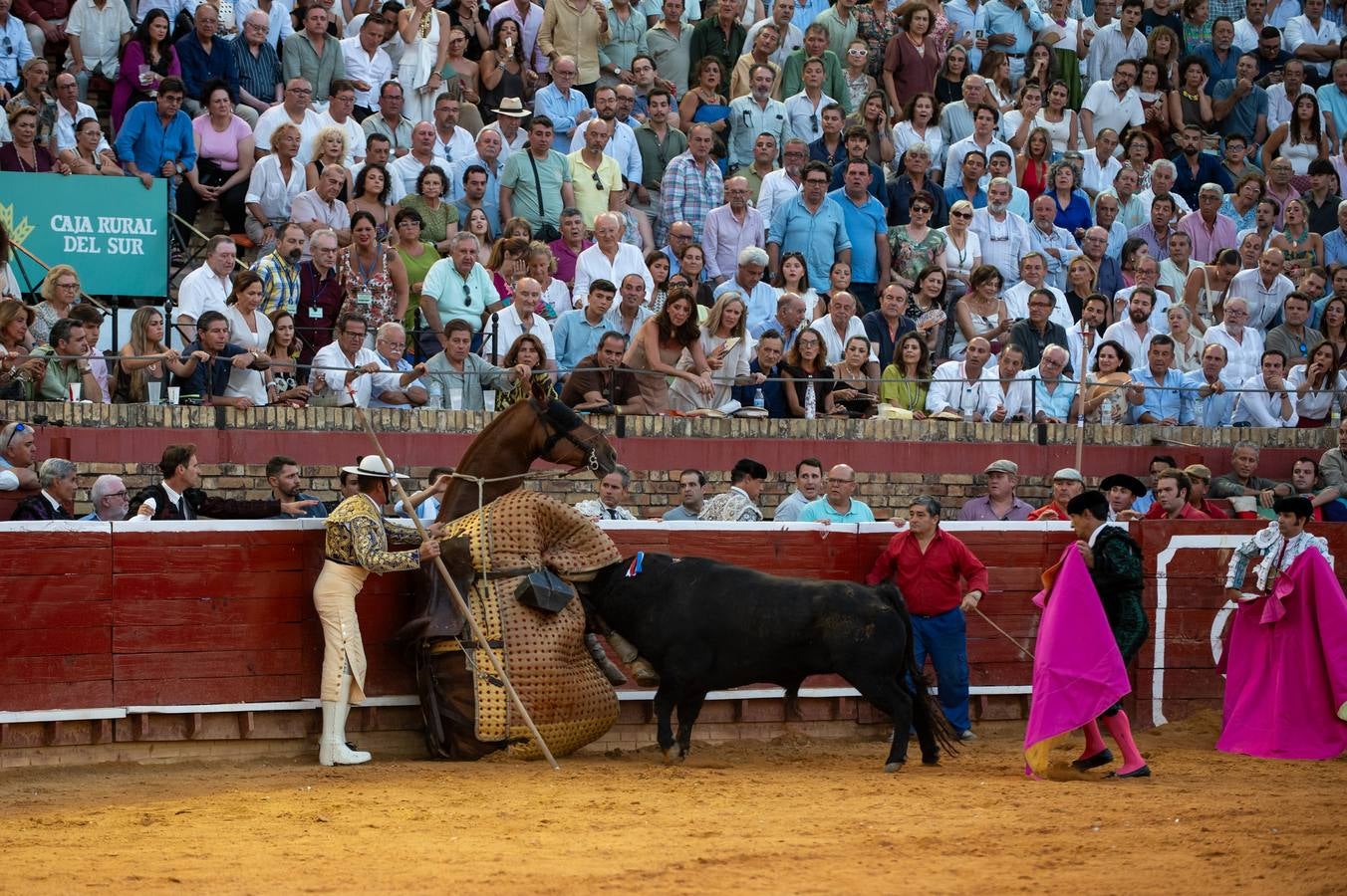 Uno de los toros embiste al caballo contra las tablas