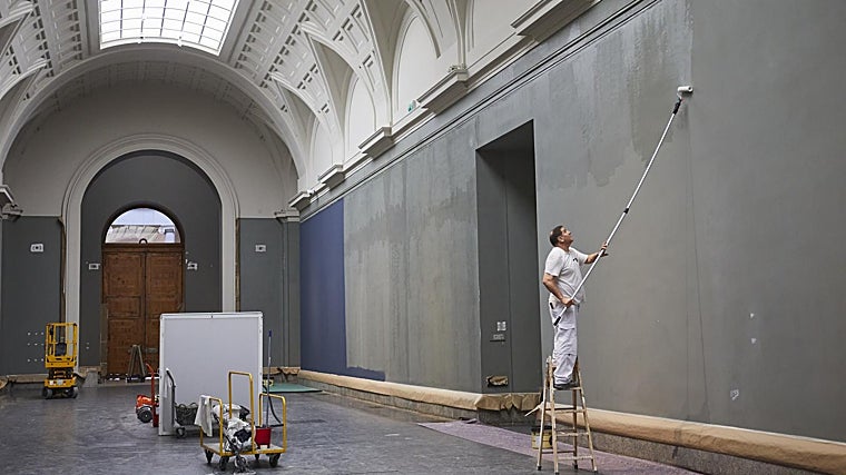 Un pintor trata las paredes de la galería central del Prado antes de pintarlas de azul