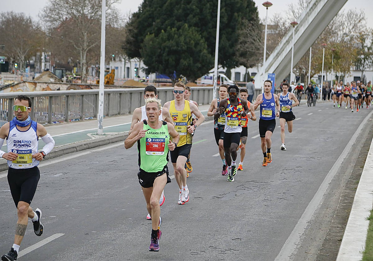 Corredores de la maratón pasan por el puente de la Barqueta
