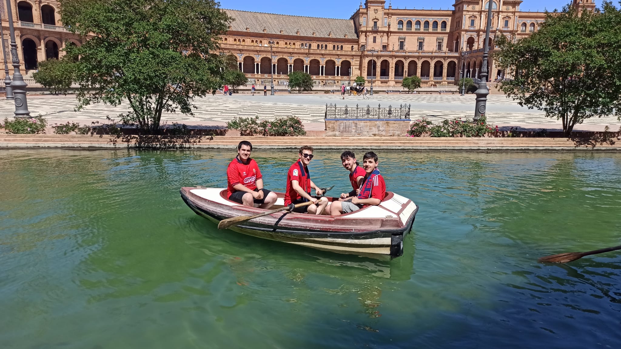 Cuatro Osasunista en una barca junto a la Plaza de España de Sevilla