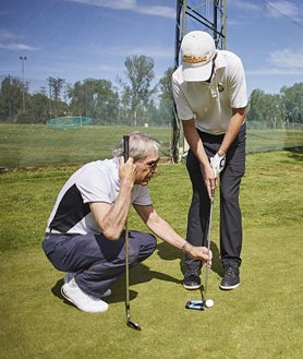 Imagen secundaria 2 - La colocación, clave . Conocedor de la pegada del jugador, su guía le sugiere el palo adecuado y le coloca correctamente para que la la bola vuele en la dirección elegida.  Unidos entre golpes . Con la ayuda de un palo de golf, que cada uno agarra desde un extremo, los dos se encaminan al lugar donde tienen que efectuar el siguiente golpe.  En el green, precisión . Si la colocación en los golpes de vuelo es importante, mucho más a la hora de patear. Además, miden los pasos hasta el hoyo para calcular la fuerza