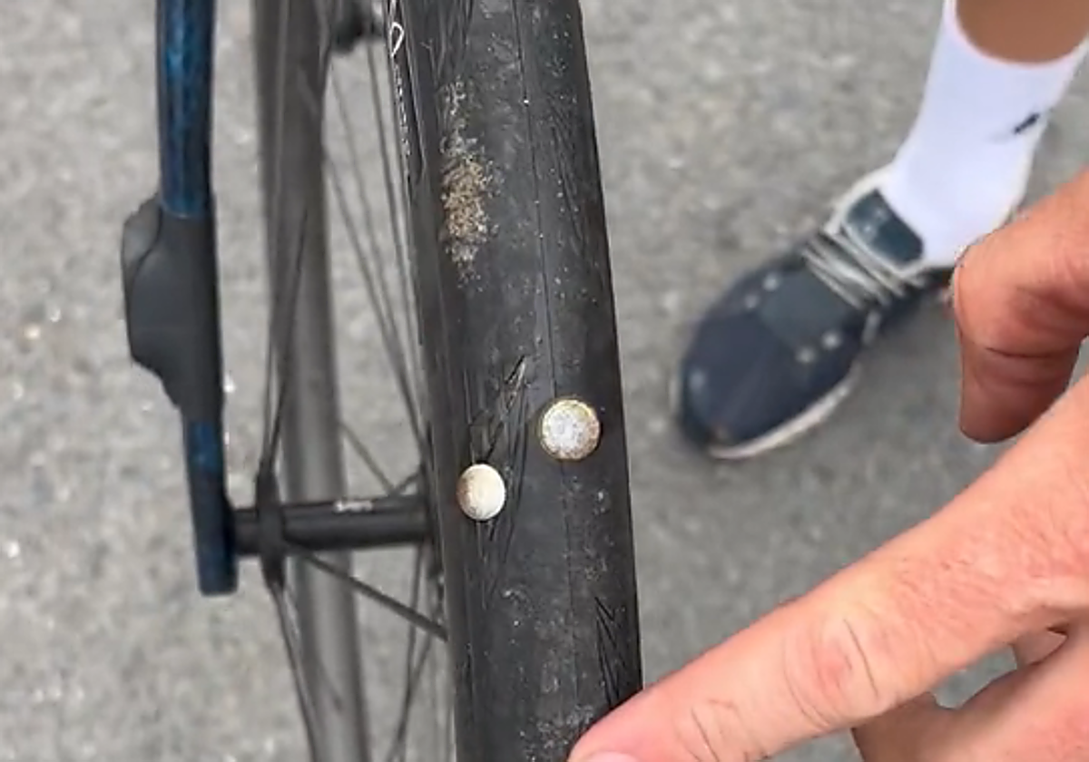 El ciclista francés Lilian Calmejane muestra la chinchetas clavas en su rueda