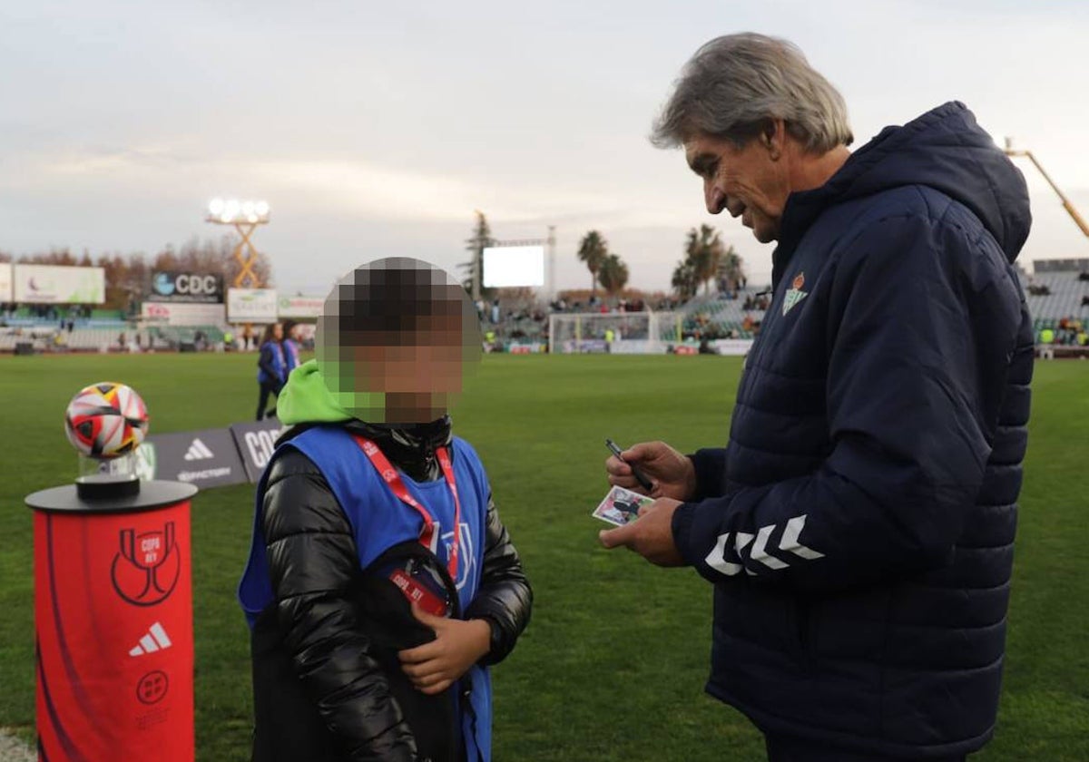 Manuel Pellegrini firma un autógrafo a un niño en los prolegómenos del Villanovense-Betis de la Copa