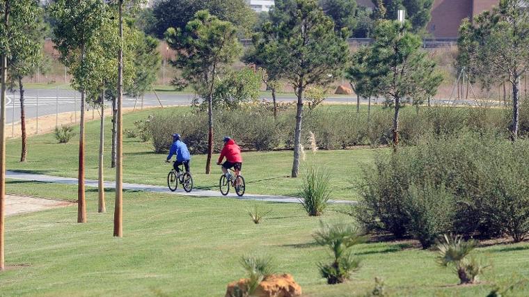 Dos ciclistas pasean por el parque Vega de Triana