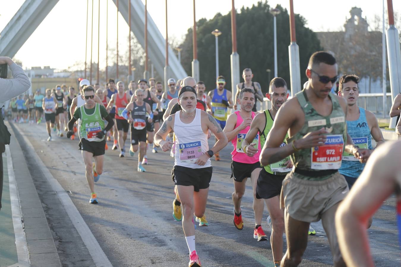 Corredores del maratón a su paso por el puente de la Barqueta