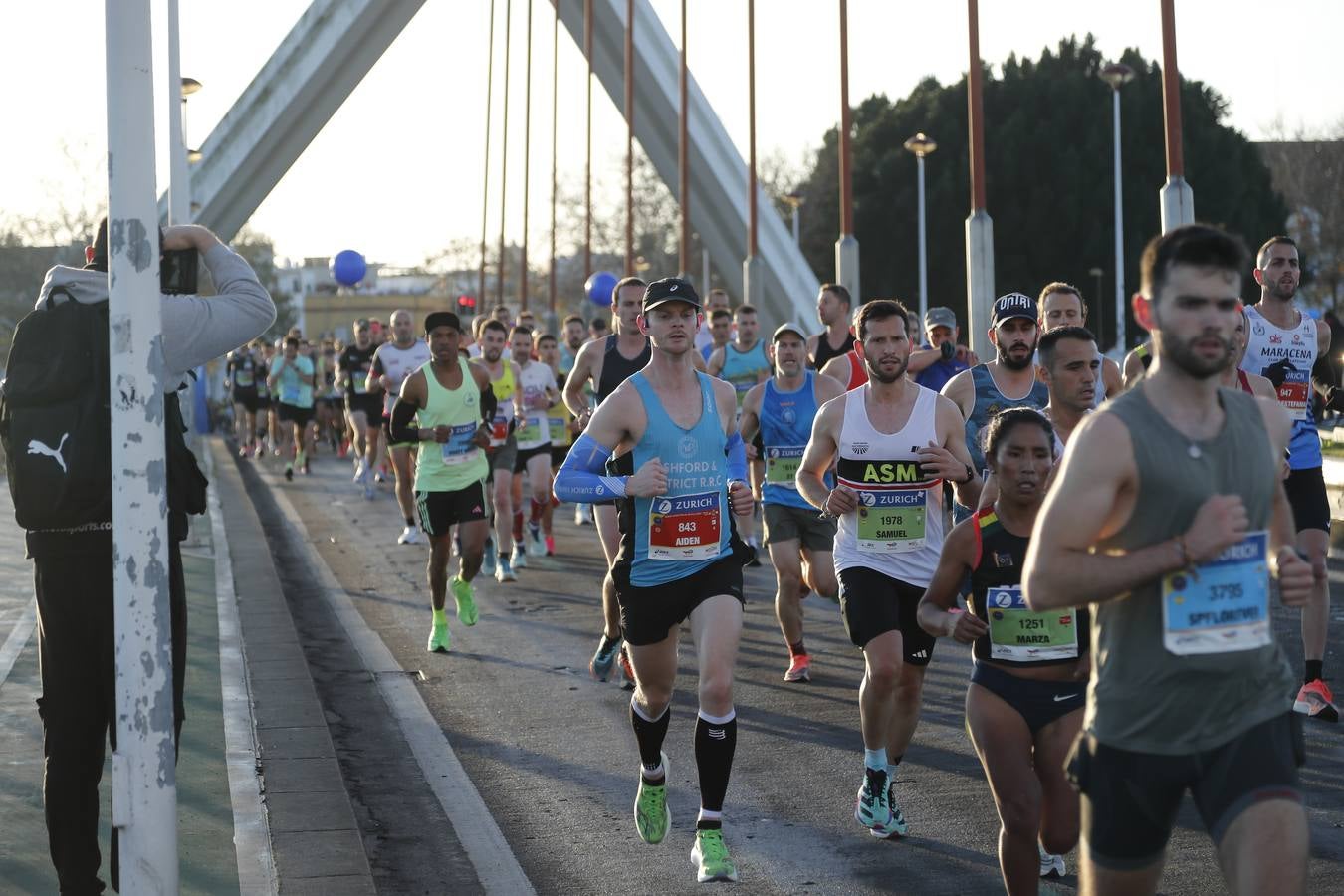 Corredores del maratón a su paso por el puente de la Barqueta