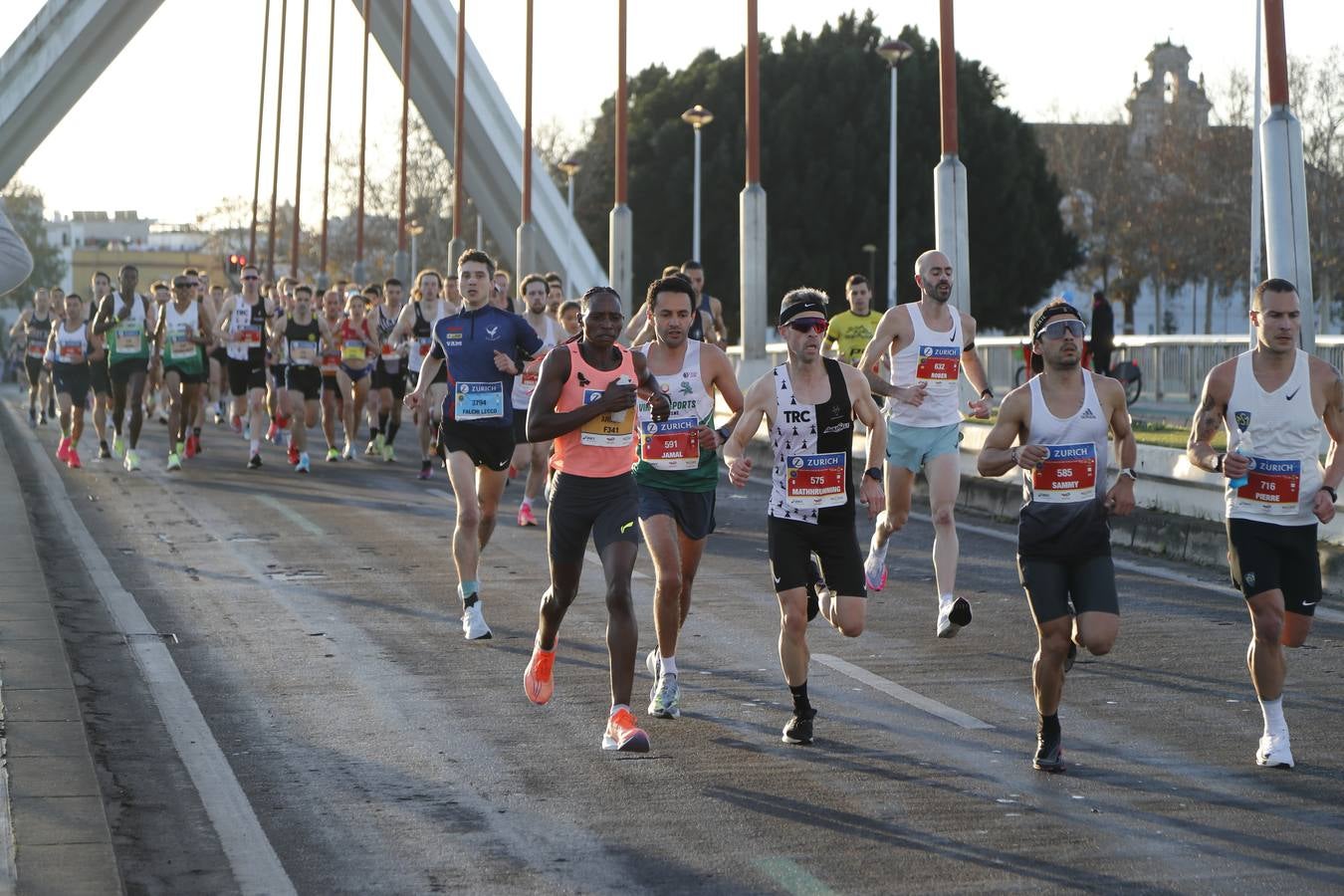 Corredores del maratón a su paso por el puente de la Barqueta