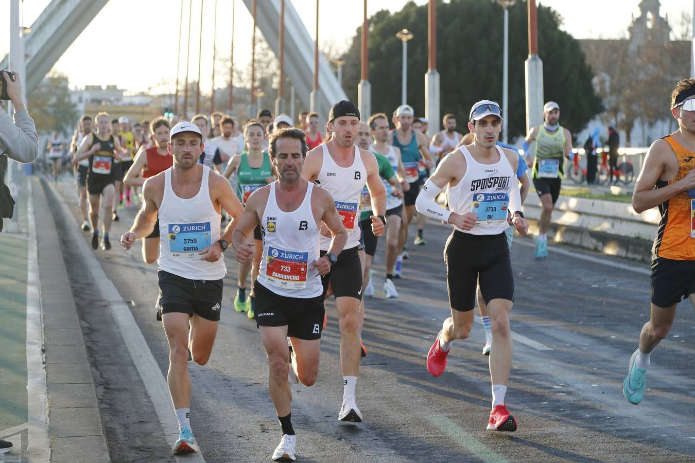 Corredores del maratón a su paso por el puente de la Barqueta