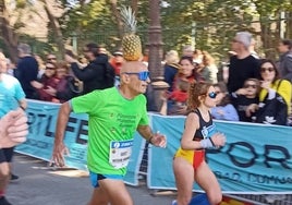 Un atleta acapara todas las miradas corriendo el Zurich Maratón de Sevilla con una piña en la cabeza