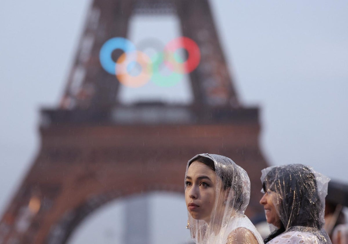 Espectadores se protegen de la lluvia durante