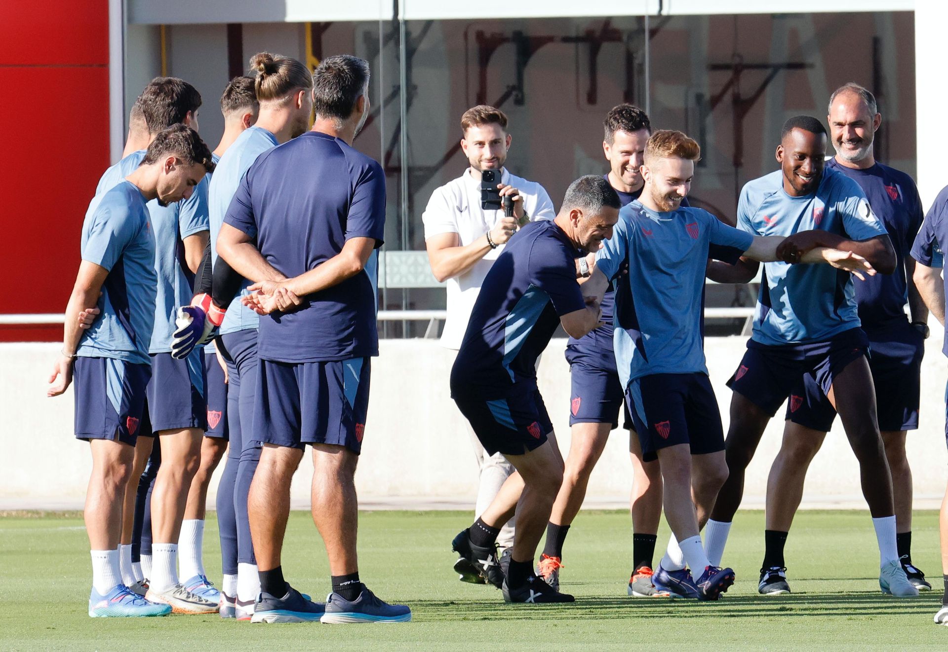 García Pimienta empuja a Peque para que sea felicitado por sus compañeros por su cumpleaños antes del entrenamiento del Sevilla FC
