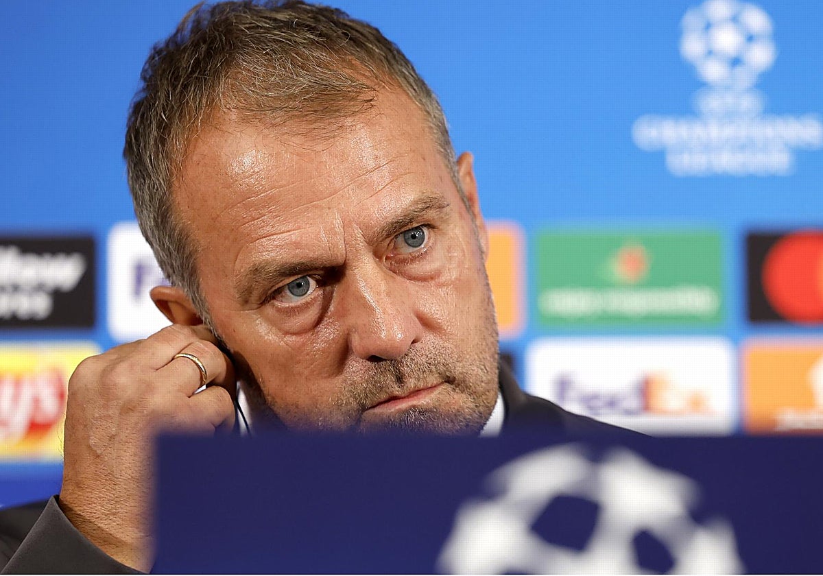 Hansi Flick se coloca bien el auricular durante la rueda de prensa