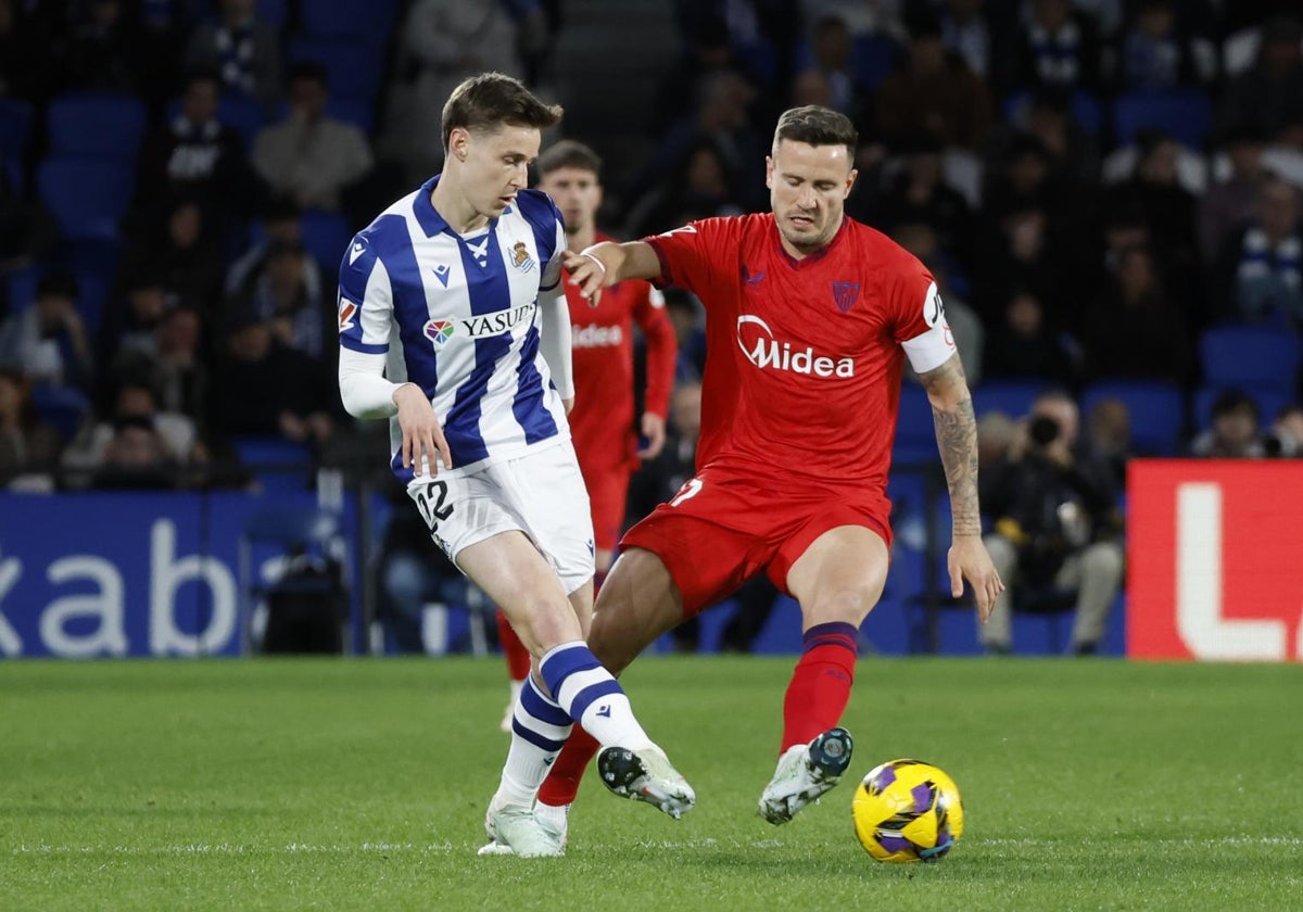 El centrocampista de la Real Sociedad Beñat Turrientes (i) centra el balón junto a Saúl Ñíguez, del Sevilla, durante el partido de la jornada 27 de LaLiga entre Real Sociedad y Sevilla FC, este domingo en el Reale Arena, en San Sebastián