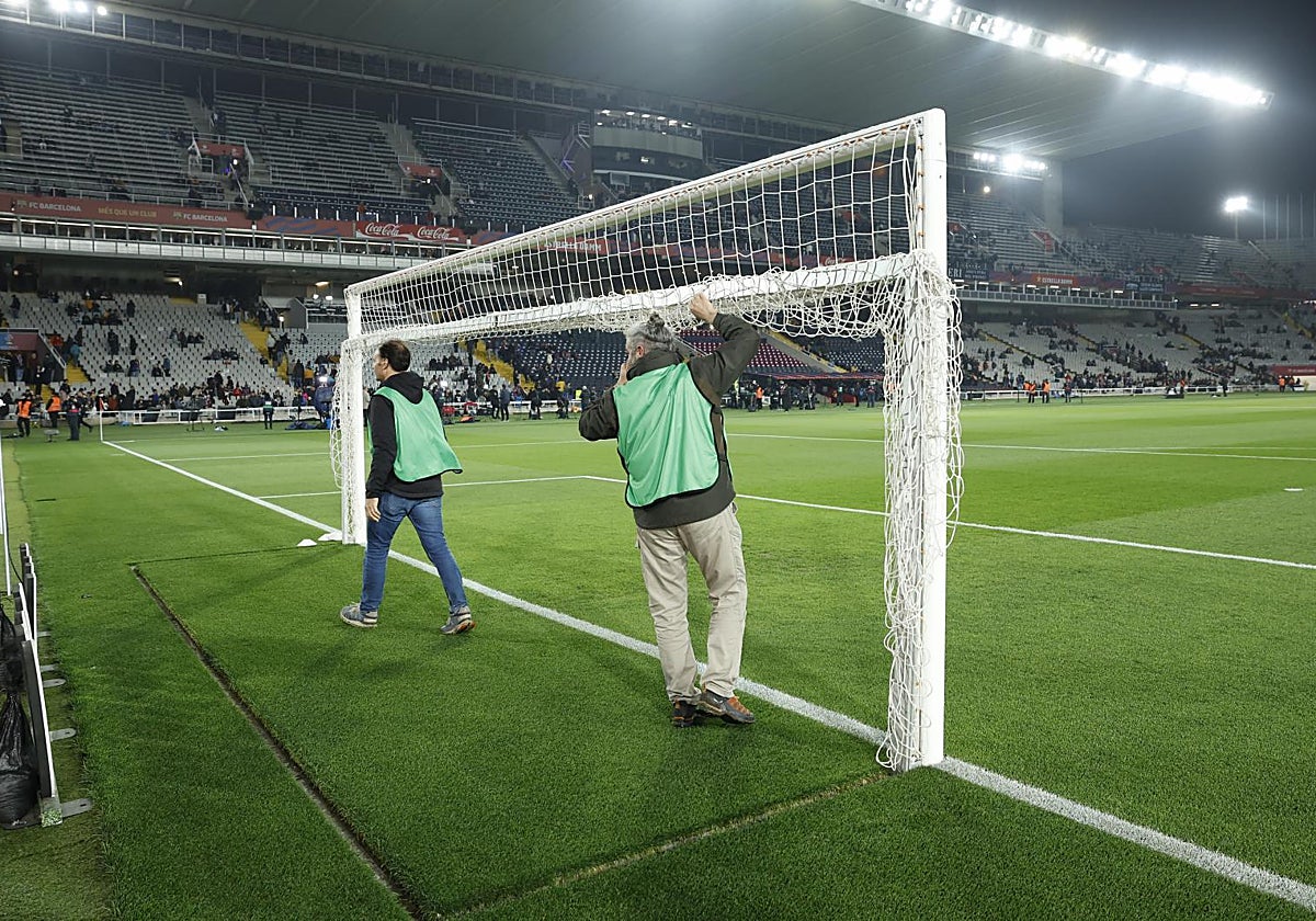 Unos operarios recogen las redes de la portería tras la suspensión del Barcelona-Osasuna