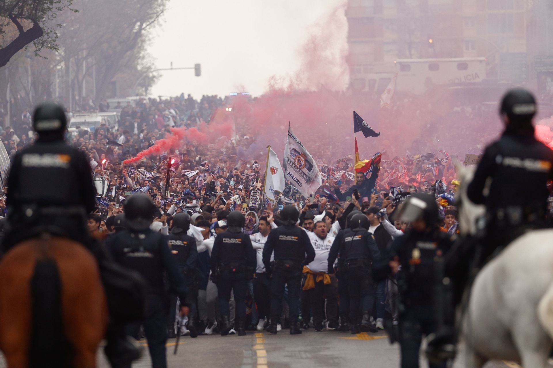 Aficionados del Real Madrid esperan al equipo ante el cordón policial.