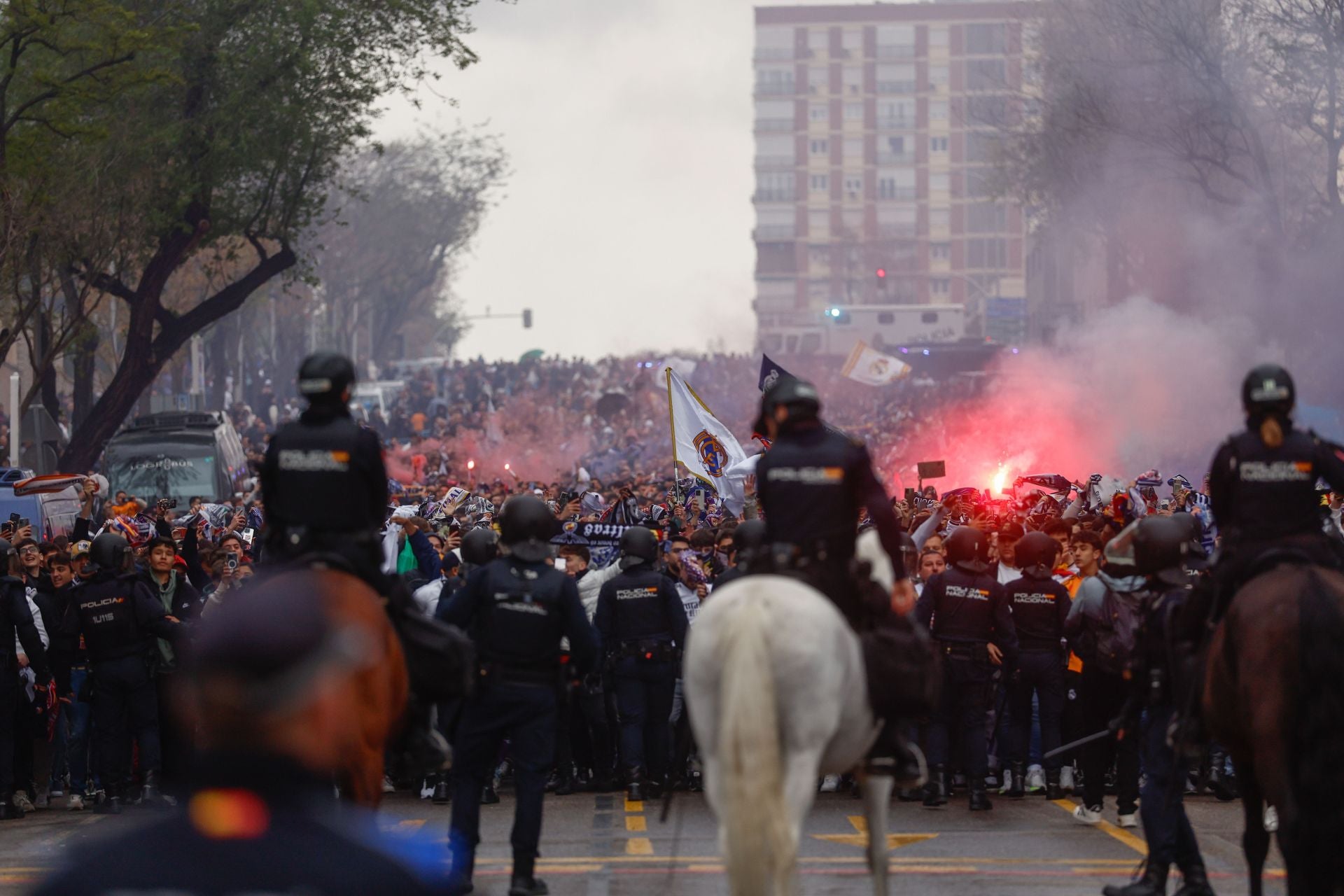 Aficionados con bengalas esperan al autobús del Real Madrid.
