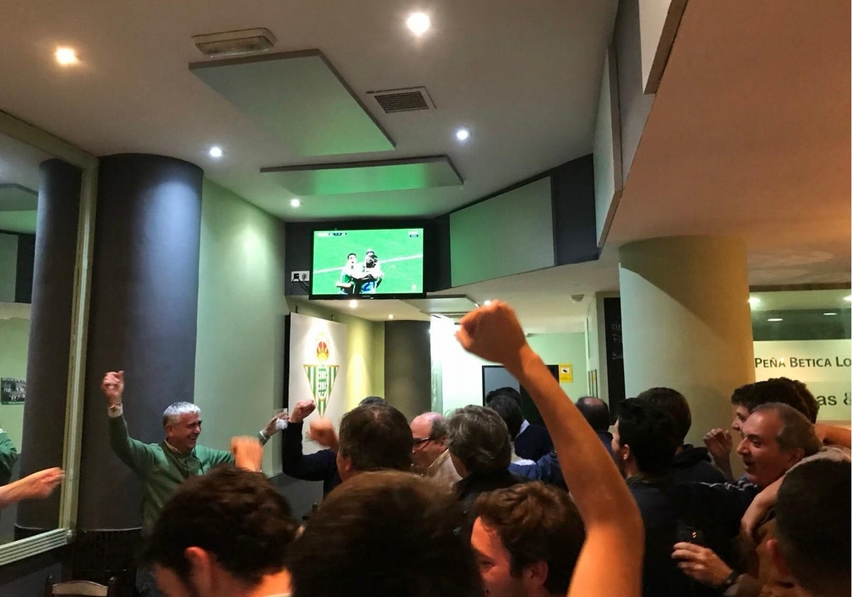 Socios de la Peña Bética Los Remedios ven un partido del Betis en su sede, situada justo enfrente del Real de la Feria
