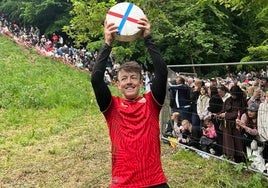 El ganador de la 'loca' carrera del queso colina abajo lo celebra ante el mundo con su camiseta del Sevilla FC