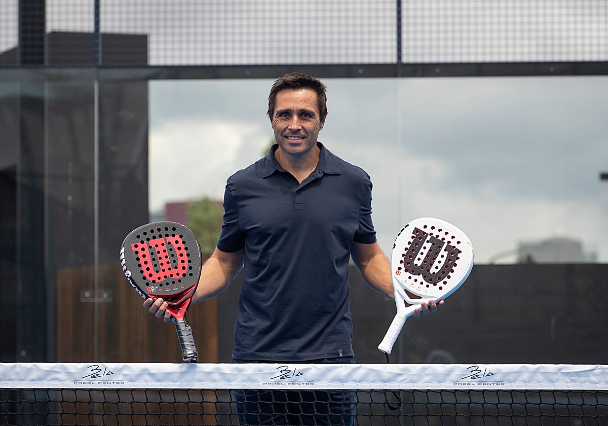 Fernando Belasteguín posando en la red del Bela Padel Center con sus palas