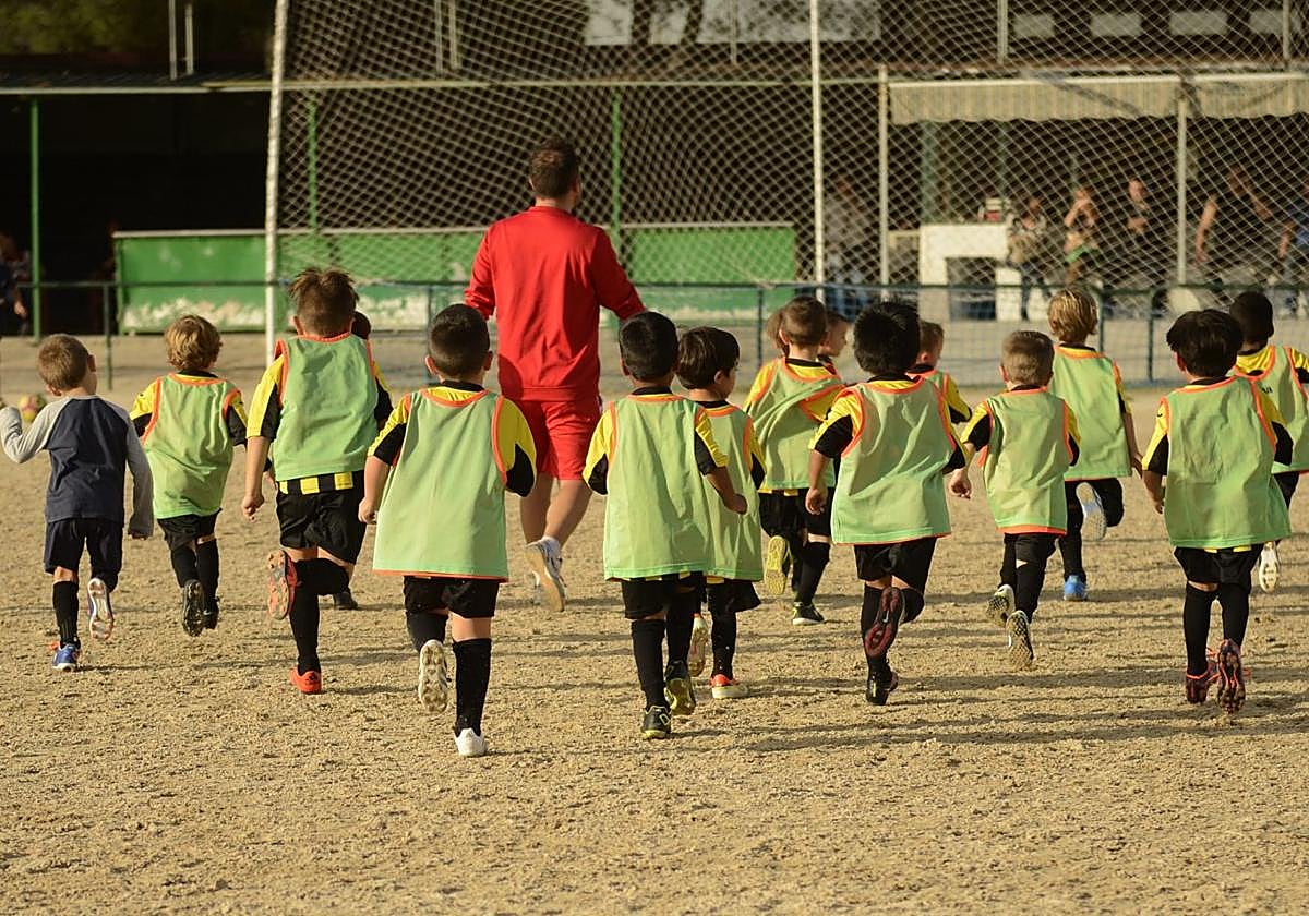 Niños jugando al fútbol en un campo de tierra