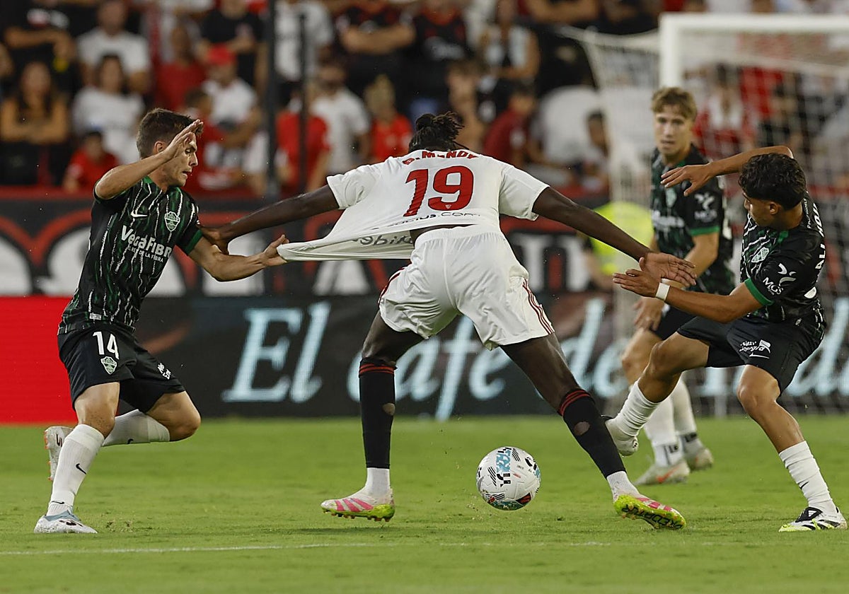 El centrocampista francés del Sevilla Batista Mendy (c) pelea un balón ante Aleix Febas y Ali Houary (d) del Elche este viernes, durante el partido de la jornada 3 de LaLiga EA Sports, que disputan Sevilla FC y Elche CF, en el estadio Ramón Sánchez-Pizjuán de la capital andaluza