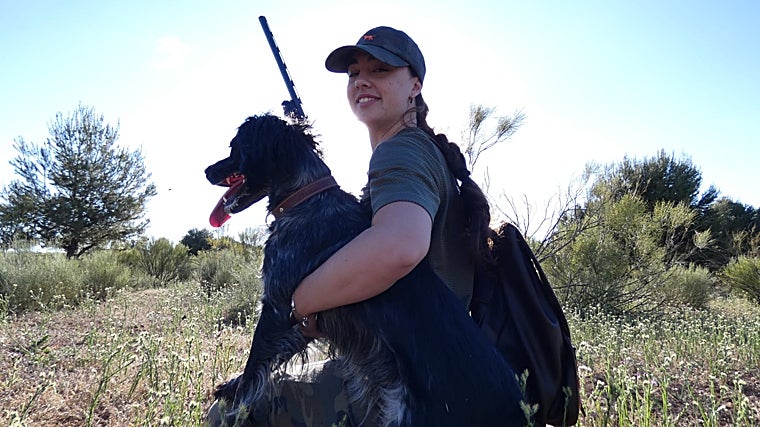 Una joven, cogiendo a un perro, durante una jornada de caza