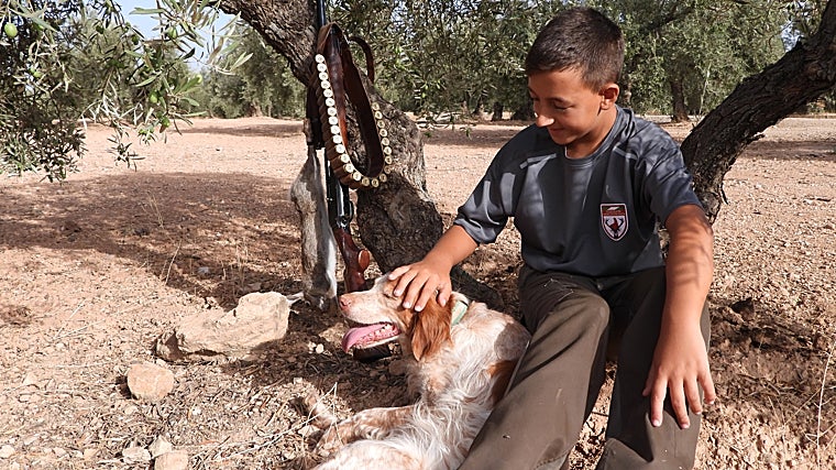 Un joven, sentado junto a un perro, descansando durante una jornada de caza