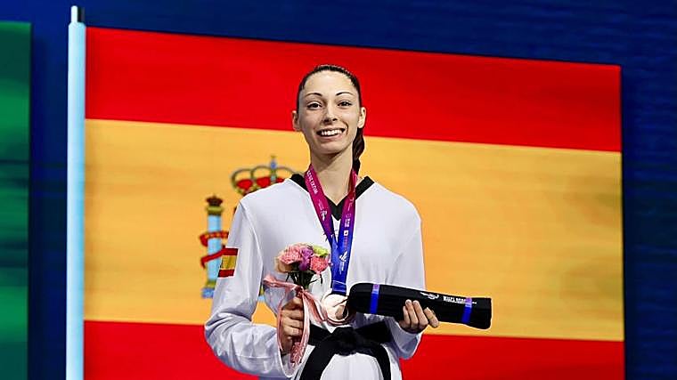 Lena Moreno posa com a medalha conquistada e a bandeira espanhola ao fundo.