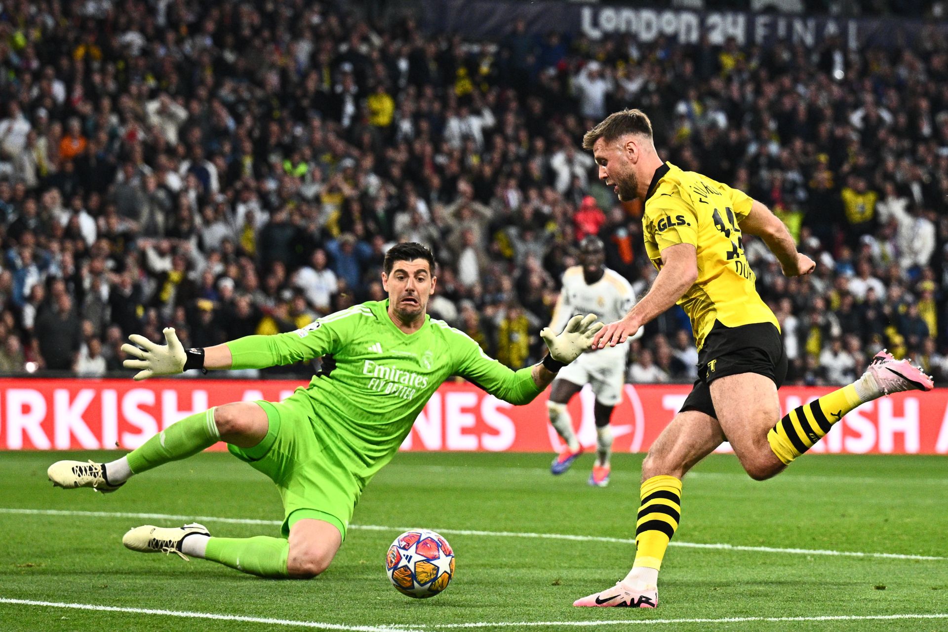 Courtois achica espacios para detener una oportunidad de gol del delantero del Borussia Fuellkrug