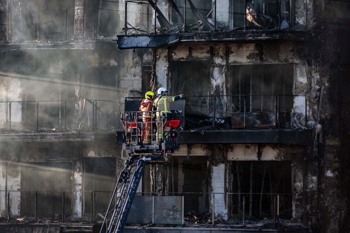 Unos bomberos inspeccionan el edificio incendiado