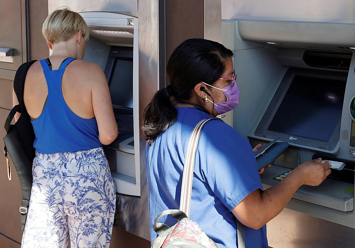 Dos personas sacan dinero de los cajeros de una entidad bancaria