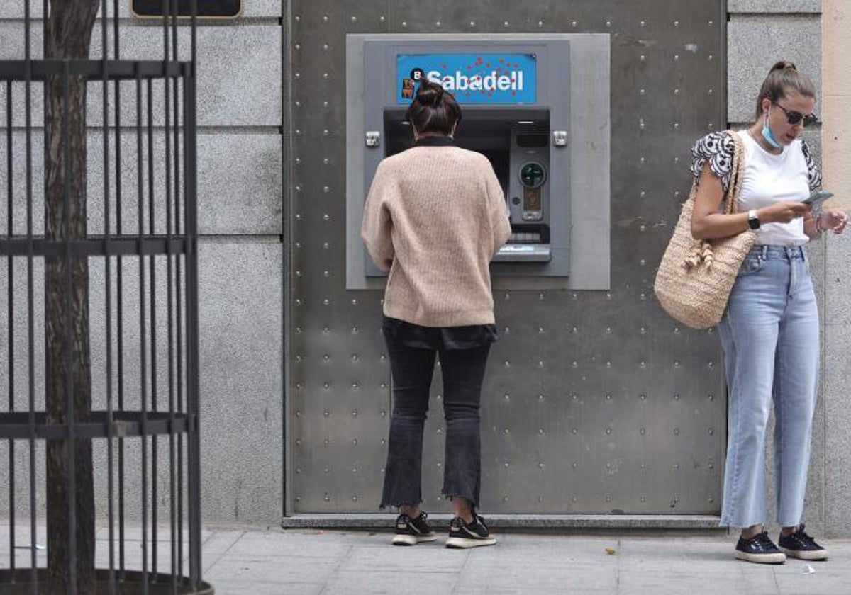 Dos mujeres realizan una operación en un cajero del Banco Sabadell