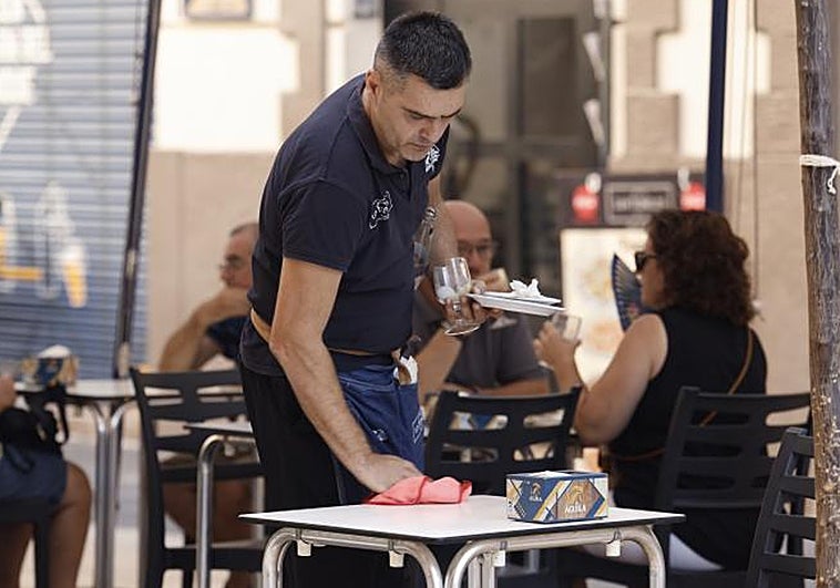 Un camarero limpia la mesa de una terraza en la ciudad de Valencia