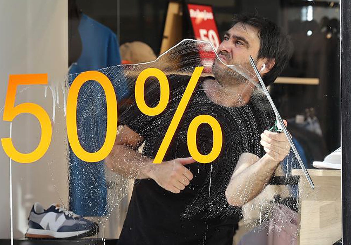 Un trabajador de un comercio limpia el escaparate en un establecimiento de Córdoba